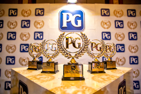 PG国际荣获的行业大奖奖杯摆放在展示台上，背景是PG的logo墙